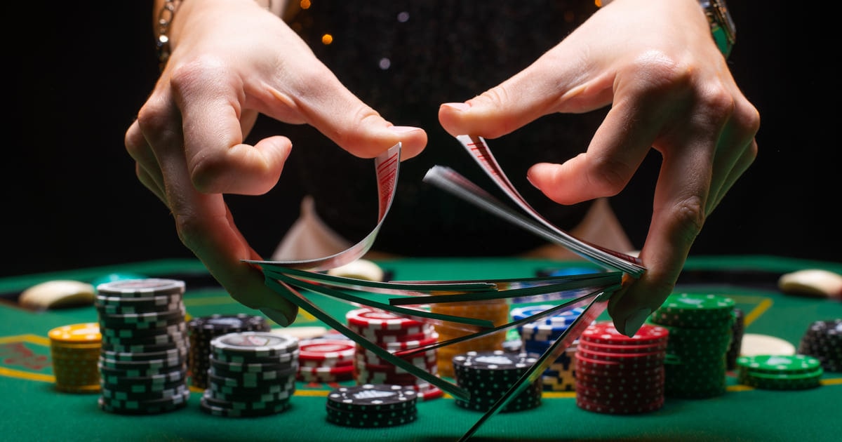 A Pair of Hands Shuffling Cards in Front of Poker Chips on a Green Felt Table